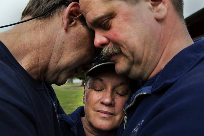 Darrington Fire District 24 volunteer firefighters, Jeff McClelland, left, Jan McClelland, center, and Eric Finzimer embrace each other Wednesday, March 26, 2014, in Darrington, Wash., after saying a prayer for the victims and survivors of the massive mudslide. They were among the first responders to the mudslide. 