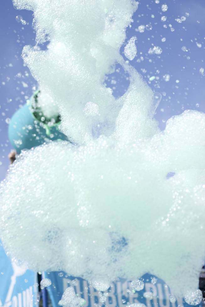 Foam is shot out at the crowd from the finish line stage during the 5k Bubble Run in downtown Las Vegas Saturday, March 29, 2014.