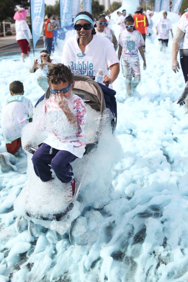A participant pushes a boy on a stroller through the blue foam bog station during the 5k Bubble Run in downtown Las Vegas Saturday, March 29, 2014.