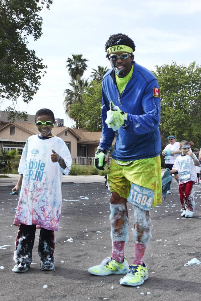 Robert Johnson, left, and his uncle, Matthew Thompson, center front, give an approving thumbs up during the 5k Bubble Run in downtown Las Vegas Saturday, March 29, 2014.