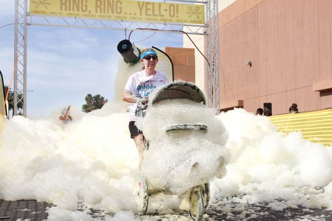A participant pushes a stroller through the yellow foam bog station during the 5k Bubble Run in downtown Las Vegas Saturday, March 29, 2014.
