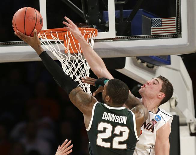 Michigan State’s Branden Dawson scores past Virginia’s Joe Harris during the second half of a regional semifinal at the NCAA men’s basketball tournament Friday, March 28, 2014, in New York. 