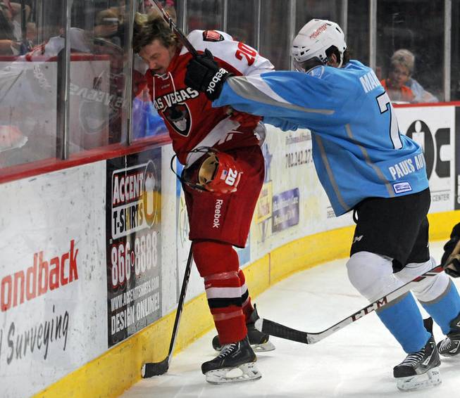 Las Vegas Wranglers forward Robbie Smith (20) takes a shot to the head near the boards from Alaska Aces defenseman James Martin (7) during the third period of play on Friday night.