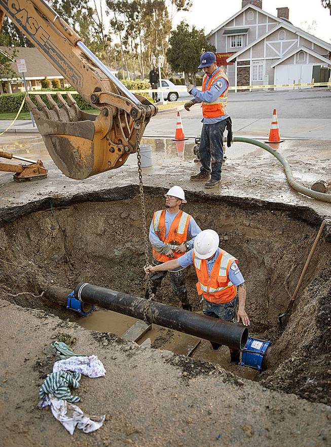 City of Fullerton maintenance workers Ernie Vejar, left, Eric Becerra and Andrew Grajeda, above, lower in a new section of pipe Saturday, March 29, 2014,   as they work on repairing a main water line in Fullerton, Calif. More than 100 aftershocks have rattled Orange County south of Los Angeles where a magnitude-5.1 earthquake struck Friday.  Despite the relatively minor damage, no injuries have been reported. (AP Photo/The Orange County Register, Ken Steinhardt)   MAGS OUT; LOS ANGELES TIMES OUT