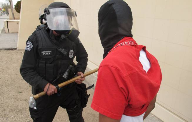 A protester faces off with an Albuquerque officer during a rally against recent police shootings in Albuquerque, N.M. on Sunday March 30, 2014.
