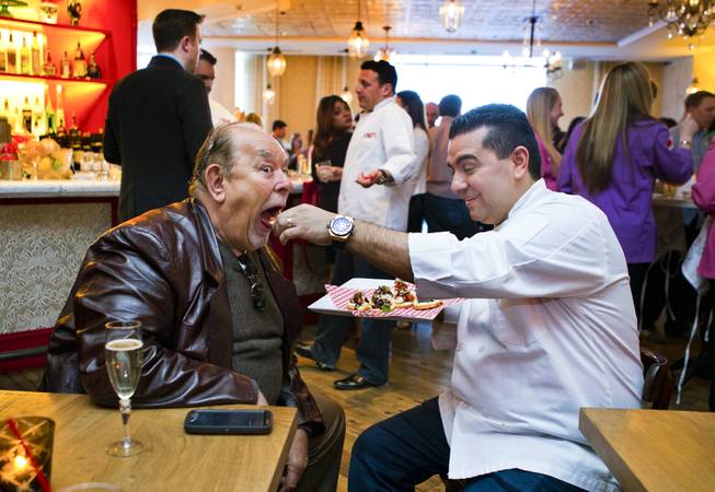 Robin Leach is fed a tasty treat by chef Buddy Valastro, who is celebrating the opening of Carlo's Bakery in the Venetian with friends on Monday, March 31, 2014.