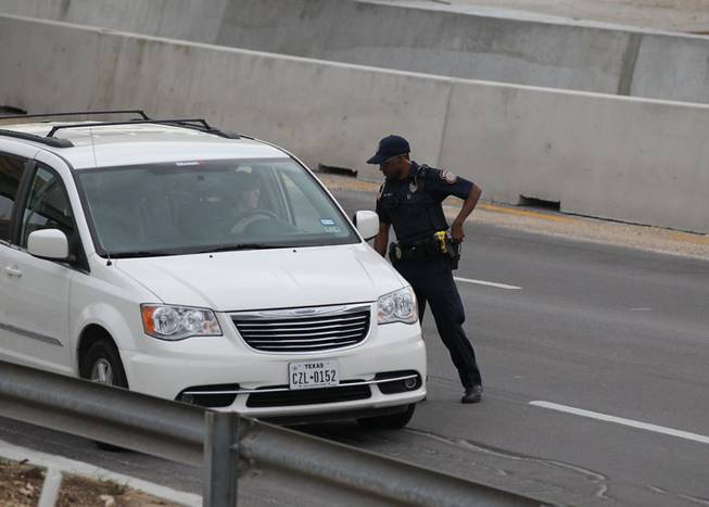 A police officer checks drivers' IDs outside the main gate at Fort Hood, Texas, after a shooting at the Army base Wednesday, April 2, 2014.  One person was killed and at least 14 injured in a shooting Wednesday at Fort Hood. 