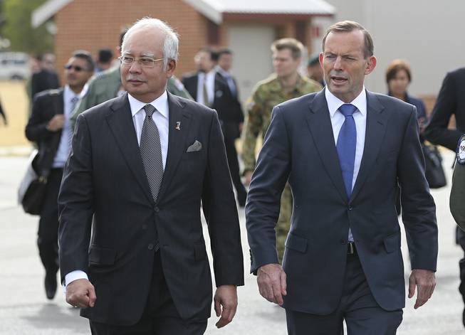 Malaysian Prime Minister Najib Razak, left, walks along the tarmac with Australian Prime Minister Tony Abbott on their way to meet crew members involved in search of wreckage and debris of the missing Malaysia Airlines MH370 in Perth, Australia, Thursday, April 3, 2014. 