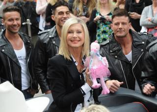 Olivia Newton-John, with Chippendales at the Rio stars Ryan Stuart, Jon Howes and Nathan Minor, makes her way to the Flamingo on Wednesday, April 2, 2014, in Las Vegas.