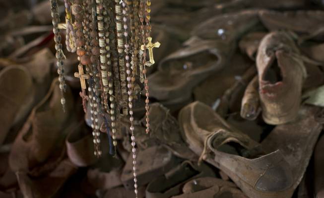 Necklaces and crucifixes hang over a pile of shoes belonging to some of those who were slaughtered as they sought refuge inside the church, which now acts as a memorial to the thousands who were killed during the 1994 genocide in and around the Catholic church in Ntarama, Rwanda, Friday, April 4, 2014.