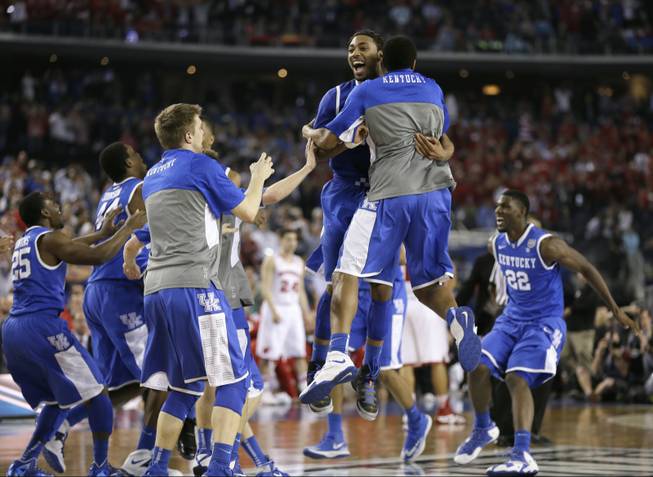 Kentucky players celebrate on the court after their 74-73 victory over Wisconsin in an NCAA Final Four game Saturday, April 5, 2014, in Arlington, Texas.