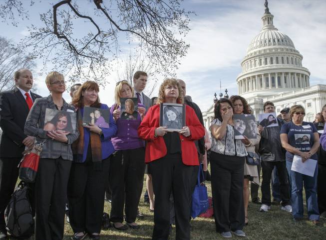 Families of victims of a General Motors safety defects in small cars hold photos of their loved ones as they gather on the lawn on Capitol Hill in Washington. Families of those who died in General Motors cars with defective ignition switches want prosecutors to go after GM insiders responsible for letting the problems fester for more than decade, and perhaps for covering them up.
