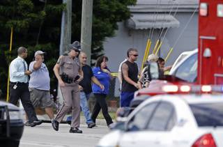 A Florida state trooper, center, escorts a group of parents to a day care center to pick up their children after a vehicle crashed into the center, Wednesday, April 9, 2014, in Winter Park, Fla. At least 15 people were injured, including children.