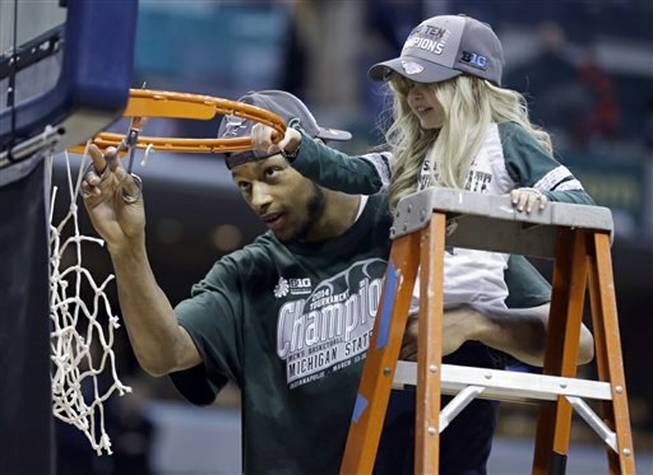 Michigan State forward Adreian Payne, left, cuts the net with Lacey Holsworth, who became close to Payne, after Michigan State defeated Michigan 69-55in the championship of the Big Ten Conference tournament on Sunday, March 16, 2014, in Indianapolis. Holsworth died of cancer on Tuesday, April 8, 2014, her family announced.