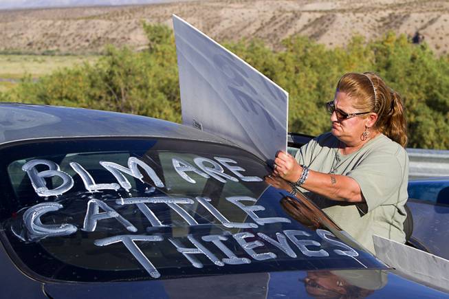 Doreen Robinson of Overton works on a sign during a protest in support of the Bundy family near Bunkerville Thursday, April 10, 2014.