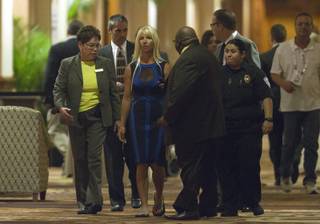 A woman, center, is led away by a security team after an object was thrown at former Secretary of State Hillary Clinton as she spoke to members of the Institute of Scrap Recycling Industries during their annual convention at the Mandalay Bay Convention Center Thursday, April 10, 2014.