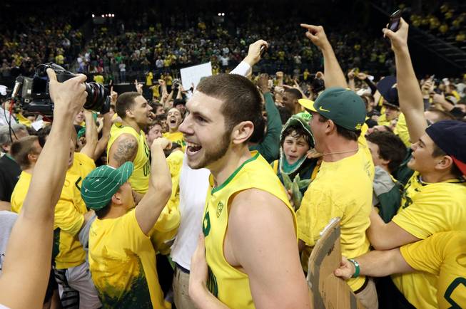 Oregon's Ben Carter, center, celebrates with teammates and fans on the court after the upset 64-57 win over Arizona in an NCAA college basketball game in Eugene, Ore. on Saturday, March 8, 2014.