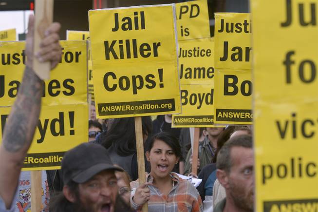 Mariee McCoy, center, of Albuquerque holds up a sign protesting Albuquerque Police Department officers during a protest that started at First and Central and marched to APD headquarters in Albuquerque on Tuesday, March 25, 2013.