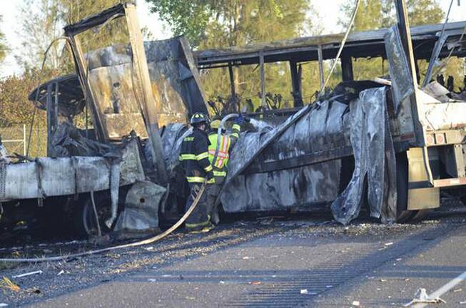 Firefighters hose down the wreckage of a bus and a semitruck that collided, Thursday, April 10, 2014, just north of Orland, Calif., that left at least nine dead. 
