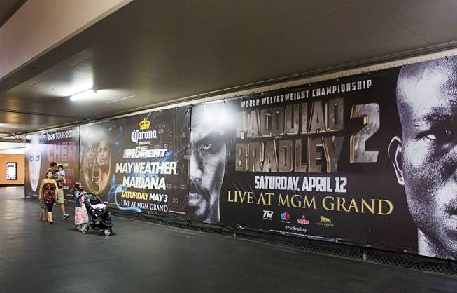 A family passes by advertisements for May 3rd Floyd Mayweather Jr. vs. Marcos Maidana fight and the April 12th Manny Pacquiao vs. Timothy Bradley fight at the MGM Grand Thursday, April 10, 2014. Top Rank CEO Bob Arum, promoter for boxer Manny Pacquiao, voiced his displeasure at the Mayweather signage during a news conference on Wednesday.