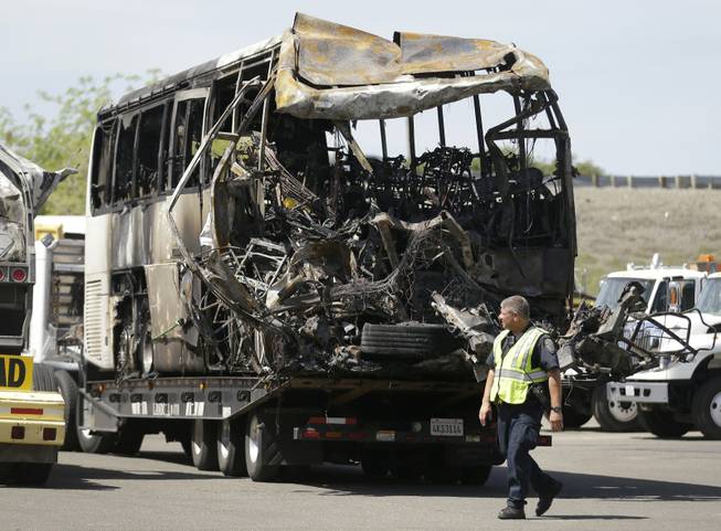 A California Highway Patrol officer walks past the charred remains of a tour bus at a CalTrans maintenance station in Willows, Calif., on Friday, April 11, 2014. 