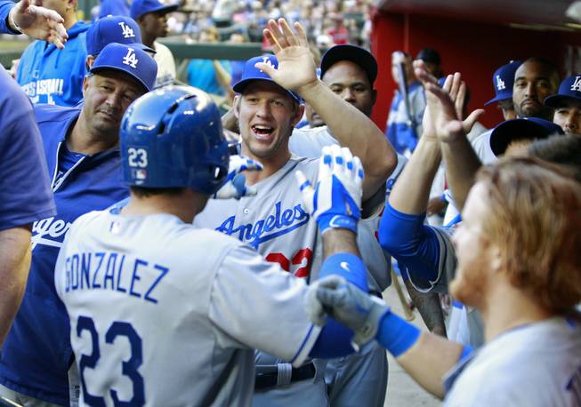 Los Angeles Dodgers' Adrian Gonzalez (23) is congratulated by Clayton Kershaw, center, and other teammates after hitting a two-run home run against the Arizona Diamondbacks during the third inning of a baseball game Saturday, April 12, 2014, in Phoenix.