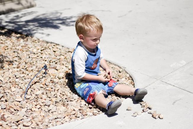 Ammon Glenn, 2, decides to play with the rocks instead of getting wet at the Kiddie Cove at Wet 'n' Wild during the first day of its weeklong spring break opening Saturday, April 12, 2014.