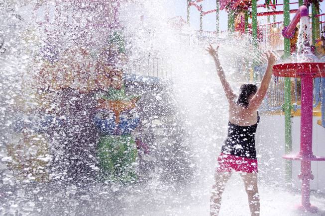 Jaclyn Wehrer gets splashed by the giant water dumping bucket at the Kiddie Cove at Wet 'n' Wild during the first day of its weeklong spring break opening Saturday, April 12, 2014.