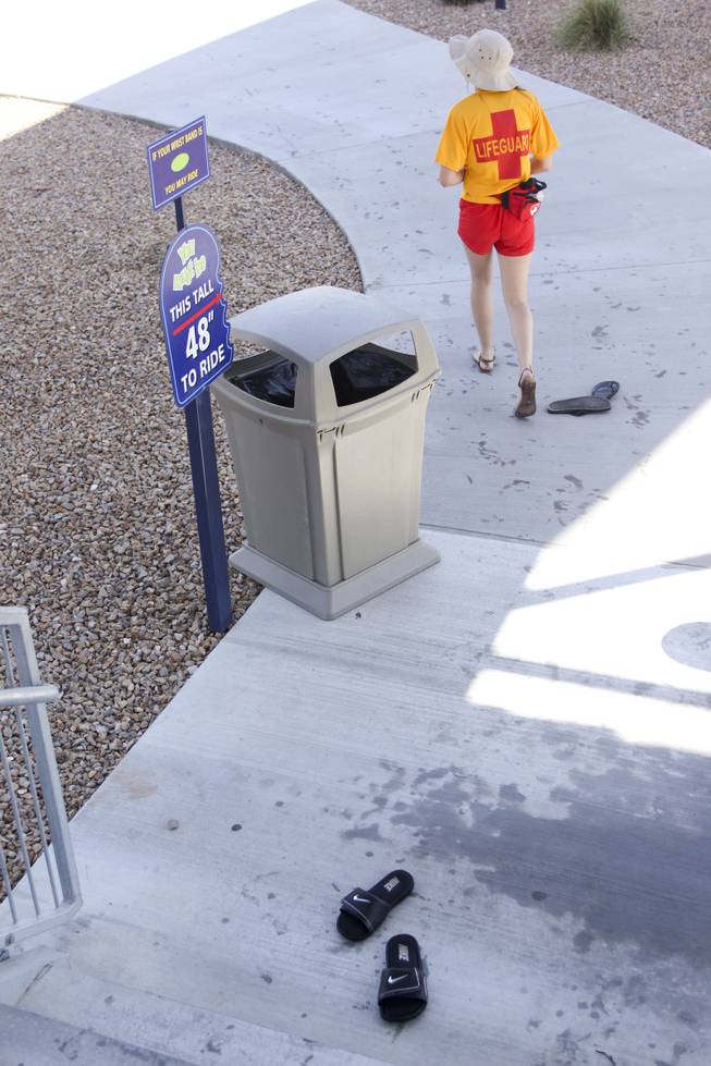 A lifegaurd walks by abondoned flip flops at Wet 'n' Wild during the first day of its weeklong spring break opening Saturday, April 12, 2014.