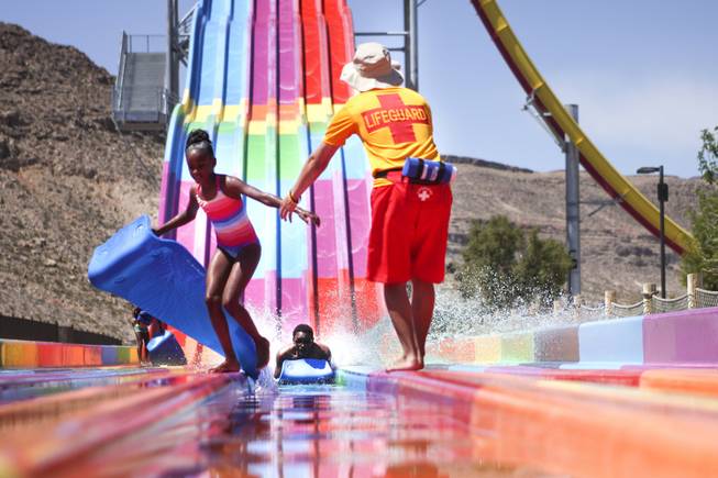 A lifeguard helps a girl get out of the way as a slider reaches the end of the Desert Racer slides at Wet 'n' Wild during the first day of its weeklong spring break opening Saturday, April 12, 2014.
