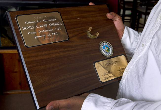 Damarlo Price holds a plaque his home on Jackson Avenue Monday, April 14, 2014. The plaque held a hammer signed by former President Jimmy Carter who attended the home dedication in 1991. The hammer was occasionally used by the family and misplaced over the years, he said.