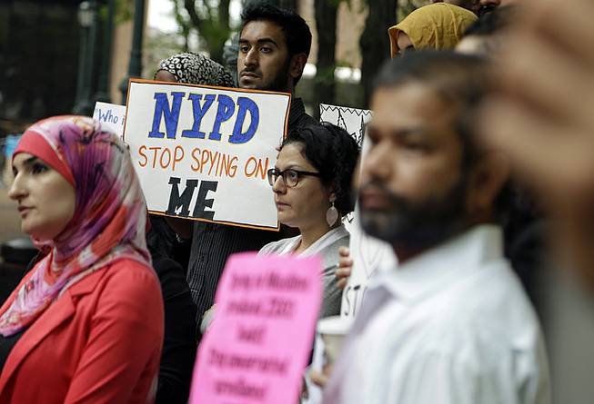 A group of people holds signs protesting the New York Police Department’s program of infiltrating and informing on Muslim communities during a rally near police headquarters in New York, Aug. 28, 2013.