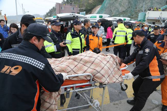 A rescued passenger from a ferry sinking off South Korea's southern coast, is carried by rescue teams on his arrival at Jindo port in Jindo, south of Seoul, South Korea, Wednesday, April 16, 2014. Dozens of military boats and helicopters scrambled Wednesday to rescue more than 470 people, including 325 high school students on a school trip, after the ferry sank off South Korea's southern coast, officials said. 