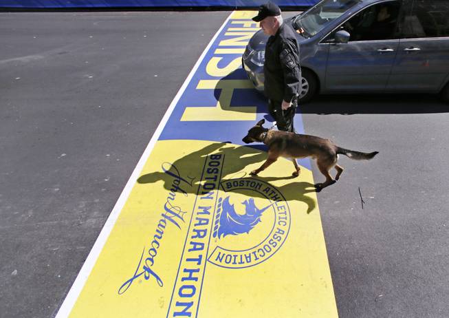 Boston Police Officer John Quinn walks with, Miller, his bomb-detection canine, over the finish line while sweeping the area in preparation for the Boston Marathon, Wednesday, April 16, 2014.