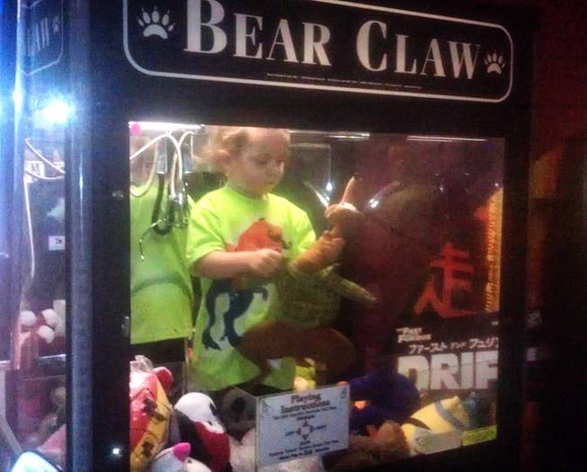 In this April 14, 2014, photo provided by Rachelle Hildreth, a 3-year-old boy plays with stuffed toys inside a claw crane game machine at a bowling alley in Lincoln, Neb.