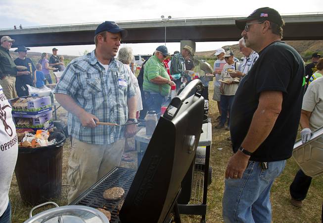 Dave Bundy, left, son of rancher Cliven Bundy, talks with Larry Skaggs of Overton, Nevada as he cooks hamburgers during a Bundy family "Patriot Party" near Bunkerville Friday, April 18, 2014. The family organized the party to thank people who supported Cliven Bundy in his dispute with the Bureau of Land Management.