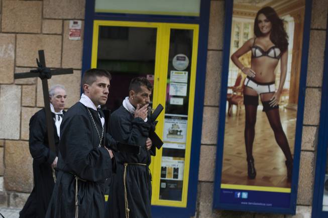 Penitents of the Jesus Nazareno brotherhood pass by a lingerie shop as they take part in a Holy Week procession in Zamora, northern Spain Friday, April 18, 2014. Hundreds of processions take place throughout Spain during the Easter Holy Week. 