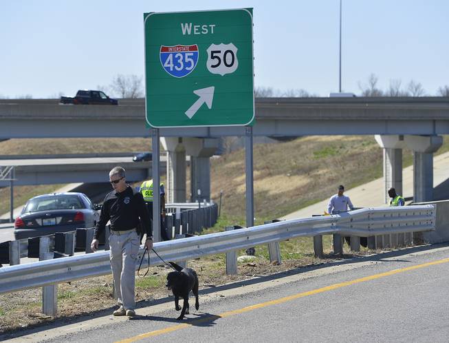 In this photo taken on Wednesday, April 9, 2014, Kansas City police and agents from the Alcohol, Tobacco and Firearms with canines investigate a shooting along southbound Interstate 435 in Kansas City, Mo.
