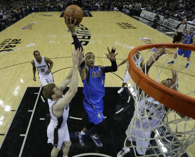 Dallas Mavericks' Monta Ellis (11) drives to the basket between San Antonio Spurs' Matt Bonner, left, and Tim Duncan, right, during the first quarter of Game 1 of the opening-round NBA basketball playoff series, Sunday, April 20, 2014, in San Antonio.