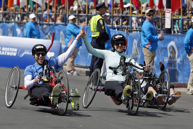 Boston Marathon husband and wife bombing survivors Patrick Downes and Jessica Kensky, who each lost a leg in last year's bombings, roll across the finish line in the 118th Boston Marathon Monday, April 21, 2014 in Boston. 