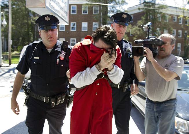 Neil K. Scott covers his face as he is led into Montgomery County Magisterial District Court, Monday, April 21, 2014, in Montgomery County, Pa. 