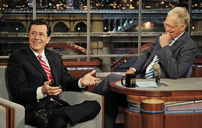 In this May 3, 2012, photo, Stephen Colbert, host of the “Colbert Report” on Comedy Central, has a laugh onstage with host David Letterman on the set of “The Late Show With David Letterman.”