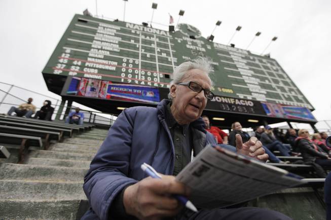 In this April 10, 2014 photo, John Weber keeps score with a pencil and scorecard as he watches a baseball game between Pittsburgh Pirates and Chicago Cubs at Wrgley Field Thursday, in Chicago. The 86-year-old retired transit worker figures he is an increasingly rare kind of baseball fan. Between batters and between pitches, most fans in the stands at Wrigley _ and everywhere else in the majors _ take their eyes off the game to peck away at smartphones, not bothering to try to figure out the baseball hieroglyphics that Weber and other purists scrawl on their cards.