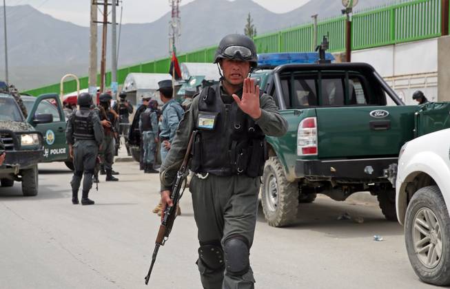 An Afghan policeman prevents journalists from approaching Cure International Hospital in Kabul, Afghanistan, Thursday, April 24, 2014. The U.S. embassy in Afghanistan says three American doctors have been killed at by an Afghan security guard who opened fire at a hospital in Kabul.