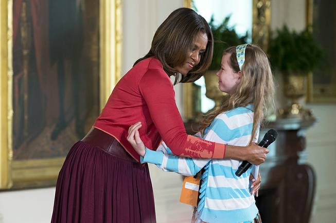 Michelle Obama hugs Charlotte Bell, 10, after she handed the first lady her dad's resume during the White House's annual "Take Our Daughters and Sons to Work Day," Thursday, April 24, 2014, in the East Room of the White House in Washington. 