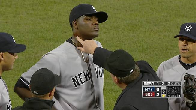 In this April 23, 2014, photo taken from video and provided by ESPN, home plate umpire Gerry Davis touches the neck of New York Yankees starting pitcher Michael Pineda in the second inning of the Yankees' baseball game against the Boston Red Sox at Fenway Park in Boston. Pineda was ejected after umpires found a foreign substance on his neck.