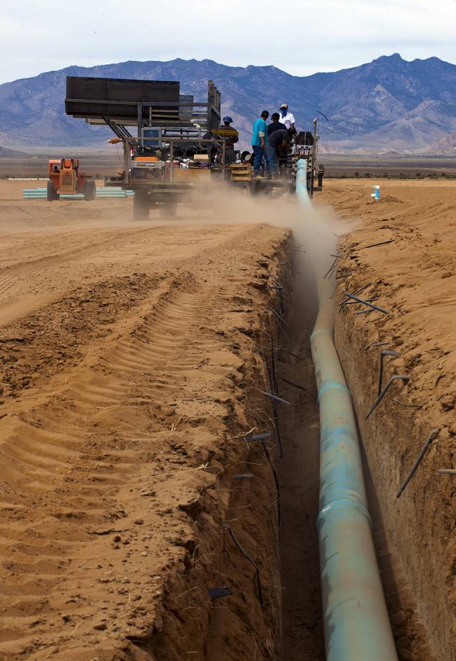 A crew works to lay more water pipe at the new Kingman Farms owned by Las Vegas developer Jim Rhodes outside Kingman, Ariz., on Wednesday, April 9, 2014.  The PipeMaster machine is an invention by Rhodes,which he says saves time, labor and makes the process safer.