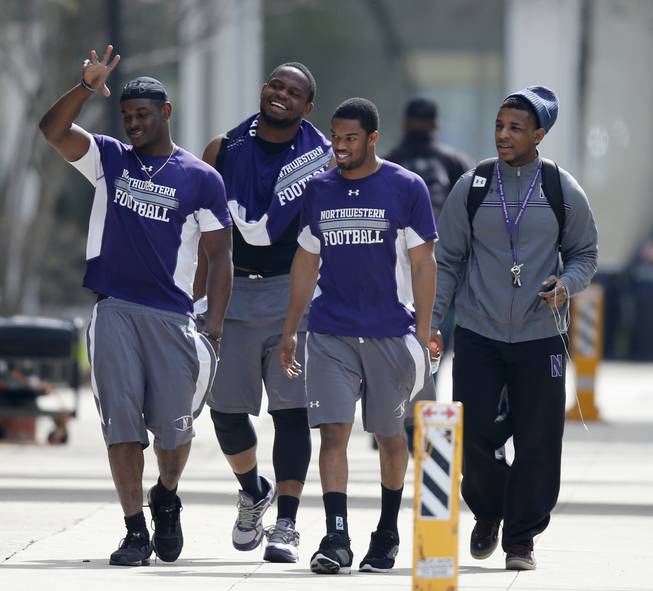 Unidentified Northwestern football players walk between their locker room and McGaw Hall, where voting is taking place on the student athlete union question Friday, April 25, 2014, in Evanston, Ill.