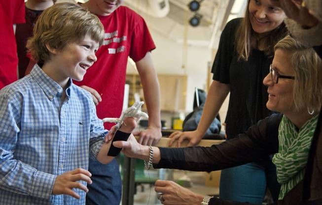 Eight-year-old Steele Songle, left, smiles at his mother Ellen after trying on an artificial hand designed by engineering students at Westtown High School, April 18, 2014, in West Chester, Pa.