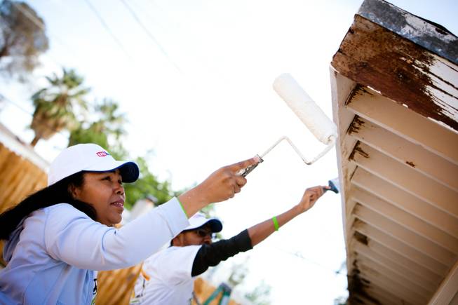 Volunteer Dionne Watson and her son, Daniel, paint the eaves of the home of former magician Gary Darwin, who lost his leg to diabetes, as part of the Rebuilding Together Southern Nevada's annual neighborhood rebuilding event in Las Vegas Saturday, April 26, 2014.